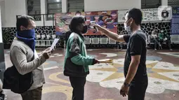 Petugas memeriksa suhu tubuh warga yang hendak mengambil BST di SMPN 3, Jakarta, Selasa (26/1/2021). Pencairan BST di Jakarta yang dilakukan Bank DKI bersama Dinsos DKI Jakarta dibatasi hanya 500 orang penerima per titik per hari demi menghindari penyebaran COVID-19. (merdeka.com/Iqbal S. Nugroho)