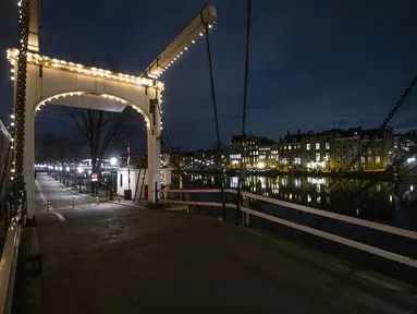 Sebuah jembatan yang sepi terlihat selama jam malam di pusat kota Amsterdam, Sabtu (23/1/2021). Belanda memasuki fase terberat dari pembatasan anti-virus Corona hingga saat ini. (AP Photo/ Peter Dejong)