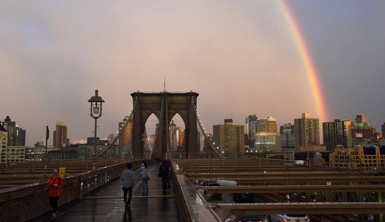 Warga beraktivitas saat pelangi terlihat dari Jembatan Brooklyn di New York City, AS (15/5). Jembatan ini selesai dibangun 1883 dan menghubungkan borough Manhattan dan Brooklyn di New York City melintasi Sungai East. (AFP Photo/Hector Retamal)