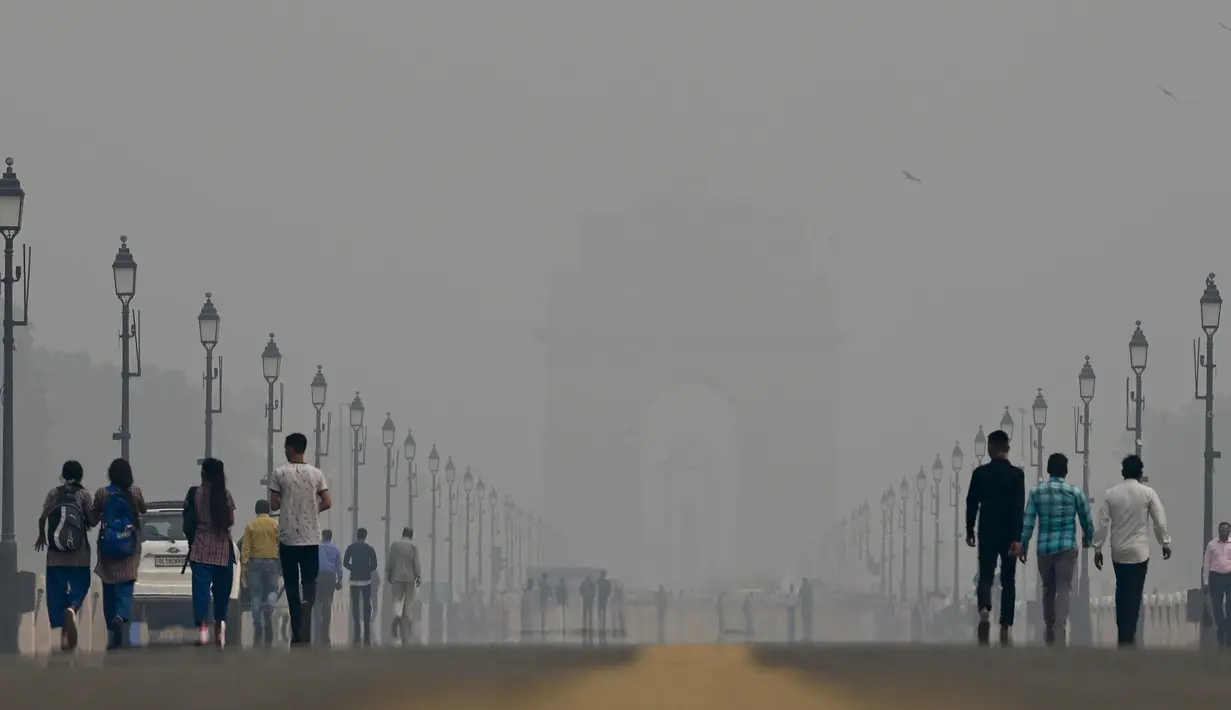 Orang-orang berjalan di sepanjang Jalur Kartavya di dekat Gerbang India di tengah kondisi kabut asap yang tebal di New Delhi pada tanggal 3 November 2023. (ARUN THAKUR/AFP)