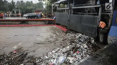 Seorang petugas membersihkan sampah yang menyangkut di Pintu Air Manggarai, Jakarta, Senin (5/2). Volume sampah terus meningkat lebih dari 200 ton. (Liputan6.com/Faizal Fanani)