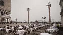 Meja-meja terlihat kosong di Alun-Alun St. Mark di Venesia, Italia, Selasa (25/2/2020). Pasien virus corona atau COVID-19 di Italia terus meningkat. (AP Photo/Renata Brito)