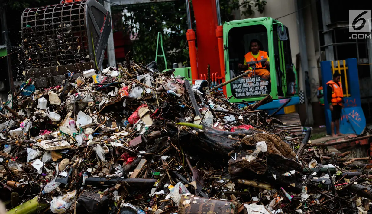 Petugas mengeruk sampah menggunakan alat berat di pintu air Manggarai, Jakarta, Selasa (4/12). Tingginya intensitas hujan di wilayah Jabodetabek membuat sampah yang terbawa arus sungai menumpuk di Pintu Air Manggarai. (Liputan6.com/Faizal Fanani)