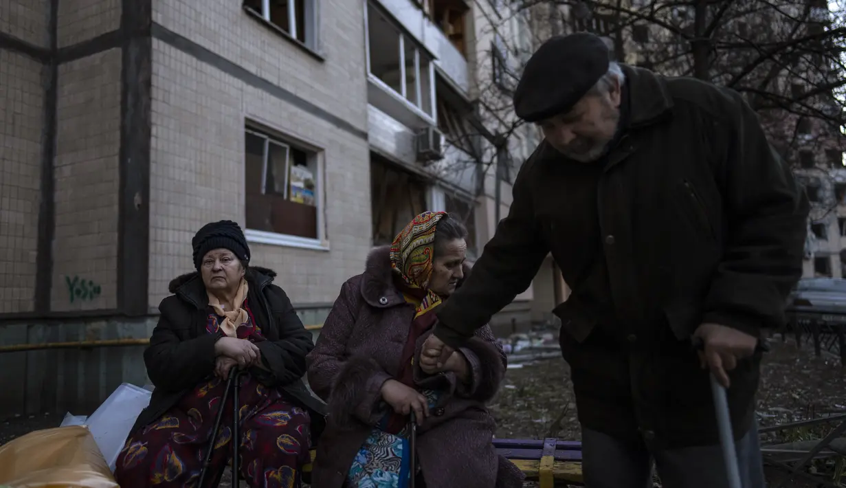 Orang-orang berkumpul di luar gedung mereka yang hancur setelah pemboman di lingkungan Satoya di Kiev, Ukraina, 20 Maret 2022. Pada Hari 25 perang Rusia di Ukraina, kehidupan yang kacau, perpisahan yang pahit tertangkap dalam foto-foto Associated Press. (AP Photo/Rodrigo Abd)