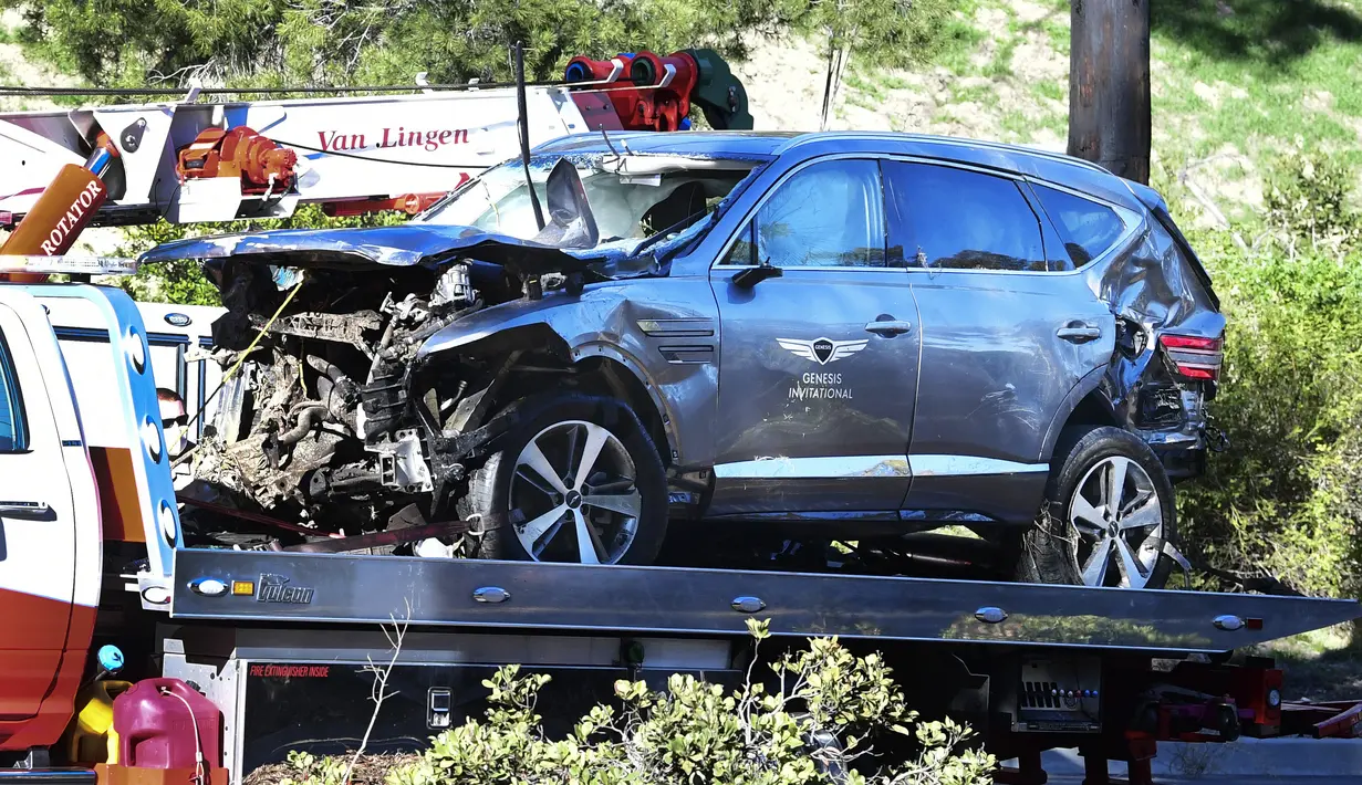 Sebuah truk derek mengangkut mobil pegolf terkenal Tiger Woods setelah kecelakaan di Rancho Palos Verdes, California, pinggiran Los Angeles, Selasa (23/2/2021). SUV itu mengalami kerusakan parah di bagian depannya dan dikelilingi serpihan dari bagian kendaraan. (Frederic J. BROWN / AFP)