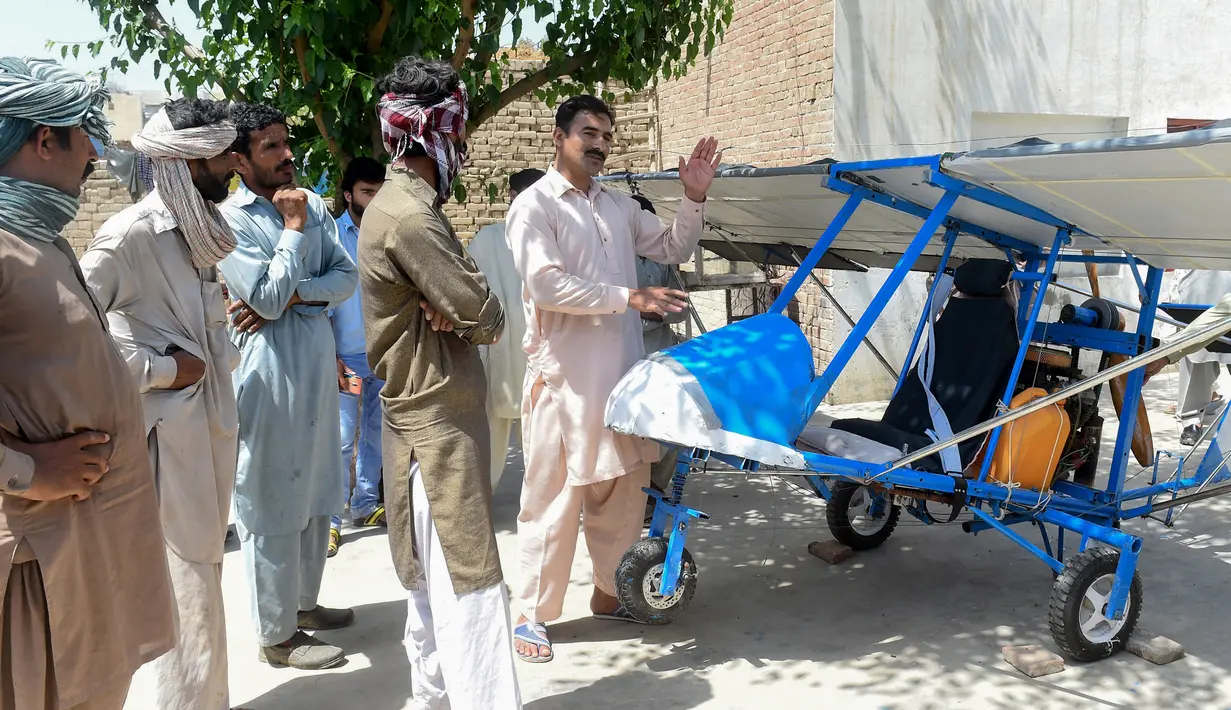 Muhammad Fayyaz berbincang dengan warga yang melihat pesawat buatannya di Desa Tabur, Provinsi Punjab, Pakistan, 8 April 2019. Karya lelaki berusia 32 tahun tersebut berhasil menarik perhatian Angkatan Udara Pakistan. (ARIF ALI/AFP)