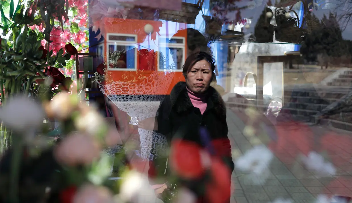 Seorang wanita terlihat di kaca jendela sebuah kios yang menjual bunga dalam perayaan Hari Perempuan Internasional di Pyongyang, Korea Utara, Jumat (8/3). (AP Photo/Dita Alangkara)