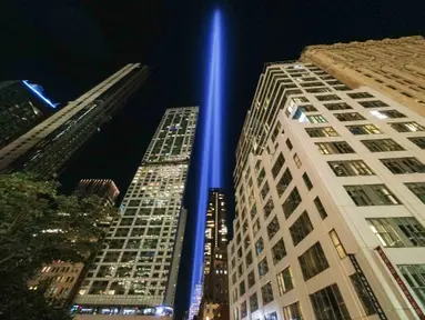 Tribute in Light tahunan memproyeksikan dua pilar cahaya ke langit malam di samping gedung-gedung yang menghadap ke 9/11 Memorial & Museum di New York City (10/9/2021). Dua cahaya kembar yang dikenal dengan Tribute in Light menyinari langit Kota New York. (AFP/Roberto Schmidt)