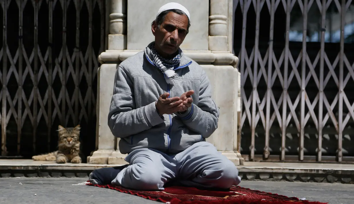 Muslim Kashmir berdoa di luar gerbang tertutup sebuah kuil muslim selama bulan puasa Ramadan di Srinagar, Kashmir yang dikuasai India (8/5/2020). (AP Photo/Mukhtar Khan)