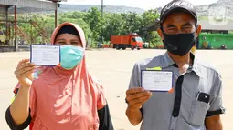 Warga menunjukkan kartu vaksin Covid-19 di TPST Bantar Gebang, Kota Bekasi (29/10/2021). Vaksinasi yang berkolaborasi dengan Sentra Vaksinasi Serviam dan Perkumpulan Pemulung Indonesia Mandiri (PPIM) bentuk komitmen jangka panjang membantu pemerintah mengatasi pandemi. (Liputan6.com/HO/Unilever)