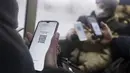 Penumpang bersiap untuk menunjukkan kode QR melalui layar ponsel pintar kepada petugas di dalam bus di Kazan, Senin (22/11/2021). Kazan, menjadi yang pertama di Rusia yang mulai mewajibkan bukti vaksinasi atau penyakit sebelumnya untuk akses transportasi umum. (AP Photo)