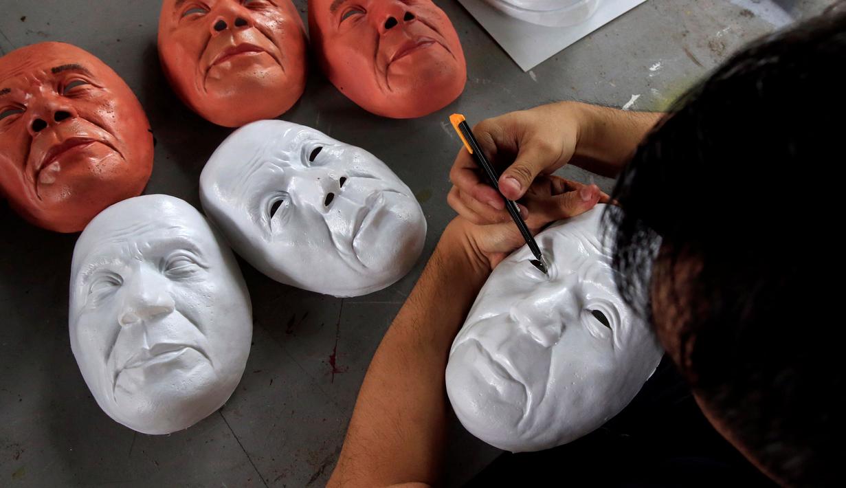 Mahasiswa seni rupa memotong topeng Presiden Rodrigo Duterte untuk perayaan Halloween di Universitas Filipina, Kota Quezon, Filipina (13/10). Topeng Duterte diyakini akan banyak diburu warga selama parayaan Halloween. (REUTERS/Romeo Ranoco)