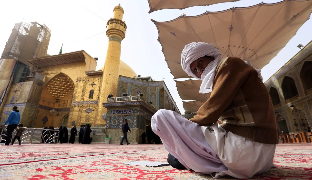 Seorang pria berdoa di luar bangunan masjid makam Imam Ali di kota Najaf, Irak (23/1). Masjid ini merupakan salah satu situs suci bagi penganut Syiah. (AFP Photo/Haidar Hamdani)