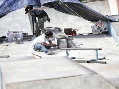 Pekerja memperbaiki arena skateboard yang rusak di RPTRA Kalijodo, Jakarta, Kamis (24/1). Perbaikan dilakukan untuk membuat rasa aman dan nyaman pengunjung yang menggunakan arena tersebut. (Liputan6.com/Faizal Fanani)