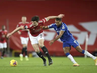 Bek Manchester United (MU), Harry Maguire bersaing dengan penyerang Everton, Dominic Calvert-Lewin pada laga pekan ke-23 Liga Inggris 2020/2021 di Old Trafford, Minggu dinihari WIB (7/2/2021). MU hanya mampu bermain imbang 3-3 saat menjamu Everton.  (Martin Rickett/Pool via AP)