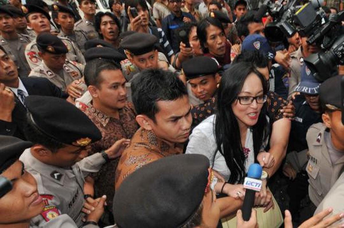 Angelina Sondakh tersenyum saat dikawal petugas keamanan KPK dan polis 