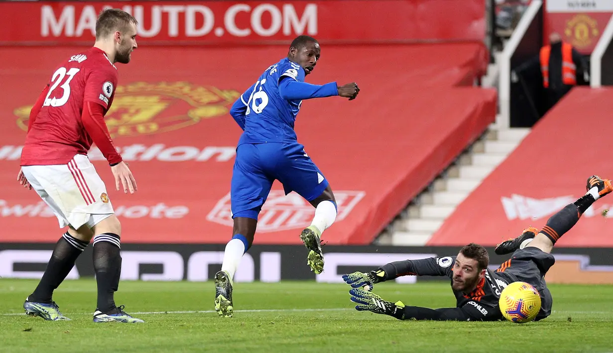 Gelandang Everton, Abdoulaye Doucoure mencetak gol pertama timnya melewati kiper Manchester United (MU), David de Gea pada laga pekan ke-23 Liga Inggris 2020/2021 di Old Trafford, Minggu dinihari WIB (7/2/2021). MU mampu bermain imbang 3-3 saat menjamu Everton. (Alex Pantling/POOL/AFP)