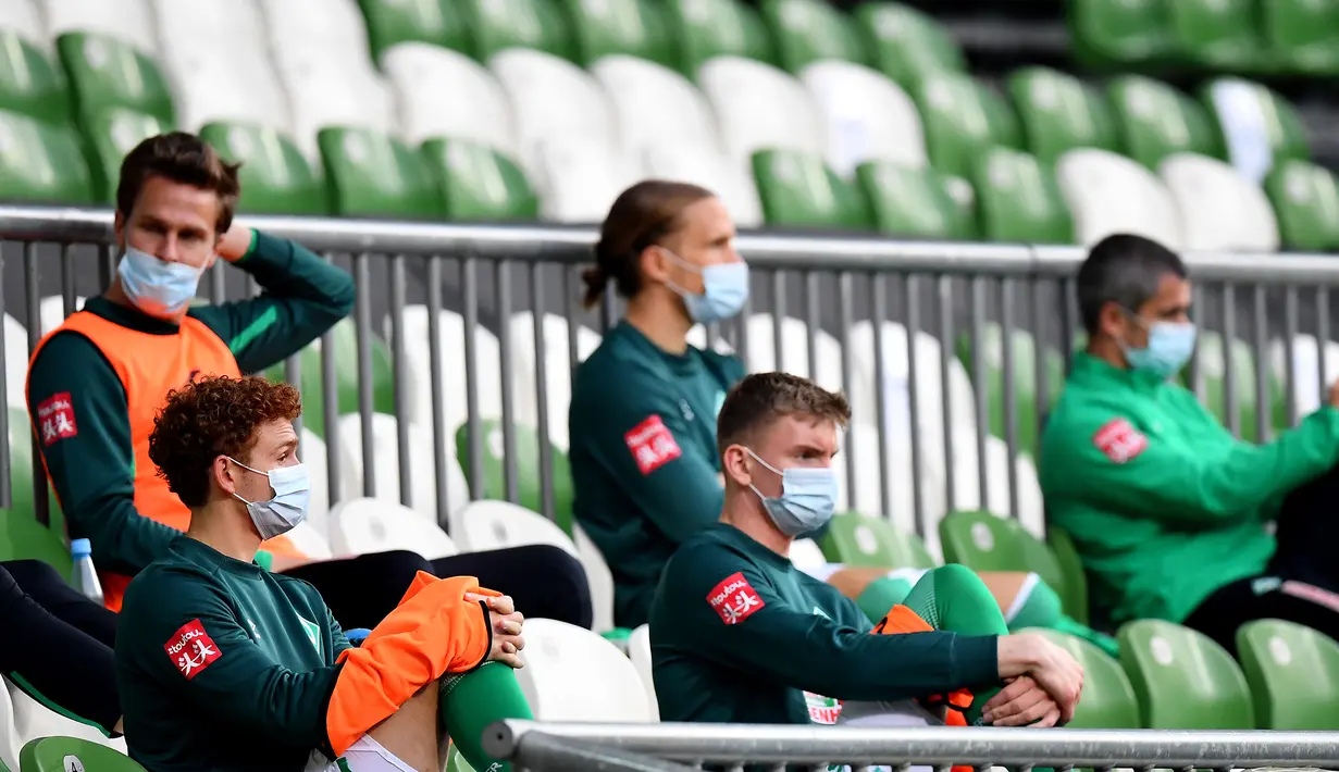 Para pemain cadangan Werder Bremen menyaksikan rekannya bertanding melawan Bayer Leverkusen dalam pertandingan Bundesliga di Bremen, Jerman, Senin (18/5/2020). Bayer Leverkusen menang 4-1. (Stuart FRANKLIN/POOL/AFP)