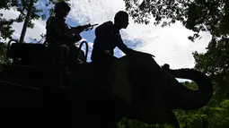 Anggota polisi militer bersama seorang pawang gajah (mahout) melakukan patroli keliling hutan dibantu gajah jinak di kawasan hutan Ulue Masen, provinsi Aceh, Sabtu (27/4/2019). Patroli keliling tersebut guna menjaga kelestarian alam dan satwa liar dari ancaman kepunahan. (CHAIDEER MAHYUDDIN/AFP)