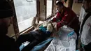 Relawan Palang Merah memindahkan seorang wanita dari tandu ke tempat tidur dalam kereta medis Medecins Sans Frontieres (MSF) atau Doctors Without Border saat mengevakuasi pasien dari dekat garis depan pertempuran ke daerah yang lebih aman di stasiun kereta di Pokrovsk, Ukraina, 7 Maret 2023. MSF merupakan kereta medis khusus yang dapat membawa pasien dari bagian timur Ukraina ke rumah sakit di bagian barat. (AP Photo/Evgeniy Maloletka)