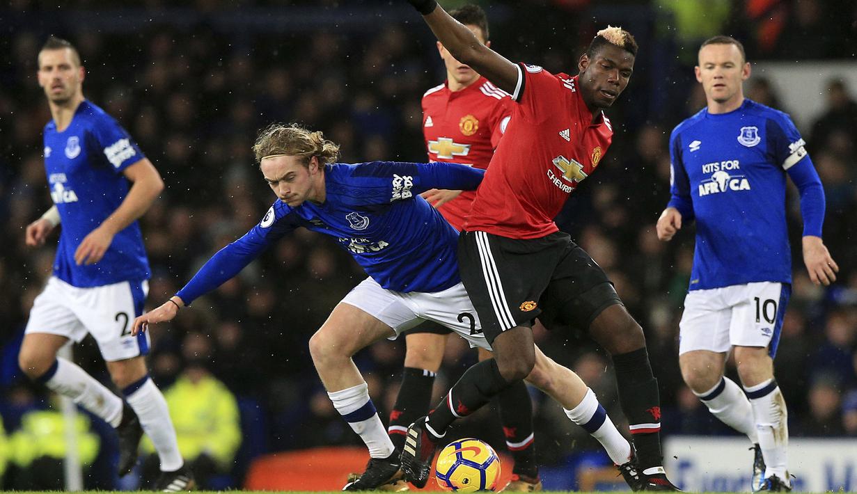 Aksi pemain Everton, Tom Davies (kiri) berebut bola dengan pemain Manchester United, Paul Pogba pada laga Premier League di Goodison Park, Liverpool, (1/1/2018). MU menang 2-0. (Peter Byrne/PA via AP)