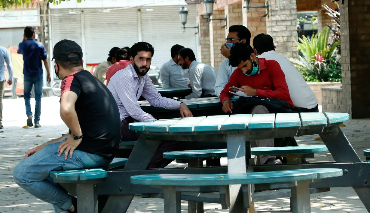 Orang-orang duduk di bangku di sebuah pasar di Rawalpindi, Provinsi Punjab, Pakistan timur  (9/5/2020). PM Pakistan Imran Khan mengatakan dalam pidatonya bahwa lockdown akan diperlonggar dalam beberapa fase mulai Sabtu (9/5). (Xinhua/Ahmad Kamal)