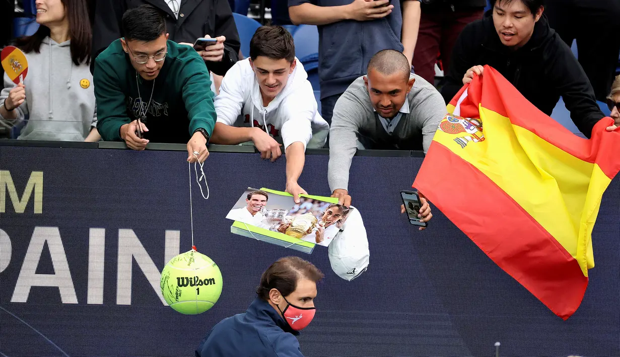 Petenis Spanyol, Rafael Nadal menghampiri para fans untuk memberikan tanda tangan usai menyaksikan timnya bertanding melawan Australia dalam Turnamen Tenis ATP Cup di Melbourne, Selasa (2/2/2021). Spanyol menang 3-0 atas Australia. (AFP/David Gray)