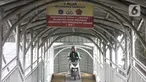 Pengendara sepeda motor melintasi rambu larangan saat melewati jembatan penyeberangan orang (JPO) Stasiun Pasar Minggu Baru, Jakarta, Selasa (10/3/2020). JPO tersebut kerap digunakan pengendara sepeda motor untuk menyeberang meski rambu larangan sudah dipasang. (merdeka.com/Iqbal Nugroho)