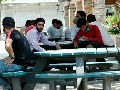 Orang-orang duduk di bangku di sebuah pasar di Rawalpindi, Provinsi Punjab, Pakistan timur  (9/5/2020). PM Pakistan Imran Khan mengatakan dalam pidatonya bahwa lockdown akan diperlonggar dalam beberapa fase mulai Sabtu (9/5). (Xinhua/Ahmad Kamal)