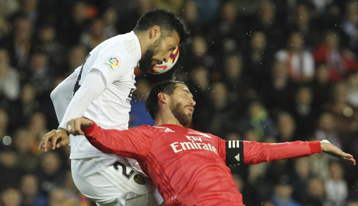 Bek Real Madrid, Sergio Ramos, duel udara dengan pemain Valencia, Ezequiel Garay, pada laga La Liga 2019 di Stadion Mestalla, Rabu (3/4). Valencia menang 2-1 atas Real Madrid. (AP/Alberto Saiz)