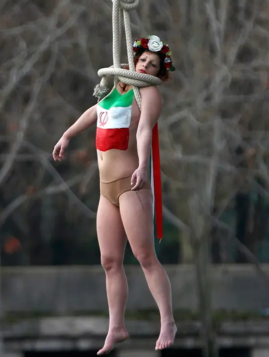 Aksi aktivis dari organisasi hak-hak perempuan Femen saat bergelantungan dari sebuah jembatan di Paris, Prancis, Kamis (28/1). Ia menggelar protes atas kunjungan Presiden Iran, Hassan Rouhani ke Paris. (REUTERS/Charles Platiau)