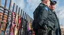 Polisi berjaga dekat deretan dasi yang digantung di pagar luar markas pemerintah Kosovo, Ibu Kota Pristina, Selasa (26/12). Pengunjuk rasa menggantungkan sekitar 300 dasi sebagai cemoohan yang ditujukan kepada PM Ramush Haradinaj. (AP/Visar Kryeziu)