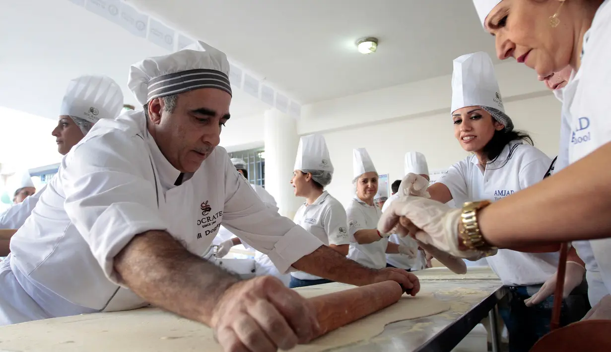 Peserta mempersiapkan adonan untuk roti manousheh raksasa di Choueifat, Beirut, Lebanon (22/11). Roti sepanjang 32 meter ini disiapkan untuk memperingati Hari Kemerdekaan Lebanon dengan tujuan memecahkan rekor dunia. (AFP PHOTO/STR)