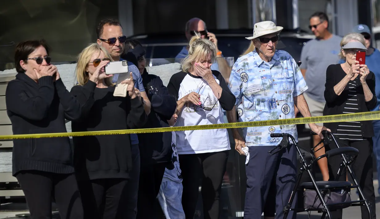 Orang-orang bereaksi melihat puing-puing helikopter Huntington Beach terangkat dari air di Pantai Newport, California (20/2/2022). Pihak berwenang sedang menyelidiki penyebab kecelakaan helikopter polisi di sepanjang pantai California Selatan tersebut. (Mindy Schauer/The Orange County Register via A