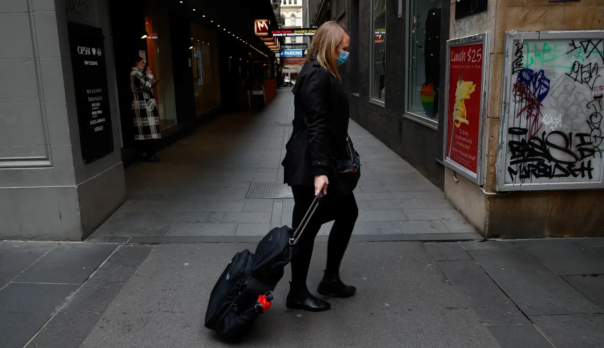 Seorang perempuan menarik tas di sepanjang trotoar di daerah pusat kota Melbourne yang tenang ketika pihak berwenang mengumumkan lockdown (penguncian) untuk keenam kalinya di kota itu dalam upaya untuk menghentikan penyebaran Covid-19 varian delta, pada Kamis (5/8/2021). (Con Chronis/AFP)