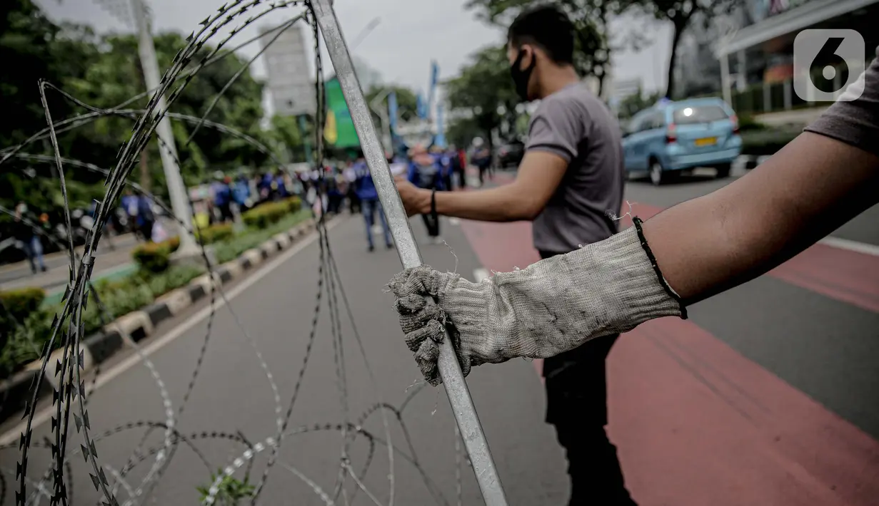 Personel kepolisian bersiap memasang kawat berduri untuk menjaga keamanan di sekitar Gedung DPR/MPR RI, Jakarta, Jumat (14/8/2020). Pengamanan ekstra itu untuk mengantisipasi rencana unjuk rasa menolak RUU Cipta Kerja yang bertepatan dengan Sidang Tahunan di Gedung DPR. (Liputan6.com/Faizal Fanani)