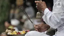 Pemuka agama menyembunyikan lonceng saat memimpin sembahyang Hari Raya Galungan di Pura Aditya Jaya, Rawamangun, Jakarta, Rabu (19/2/2020). Hari Raya Galungan yang merupakan hari kemenangan kebenaran (Dharma) atas kejahatan (Adharma) itu dirayakan setiap 210 hari sekali. (merdeka.com/Iqbal Nugroho)