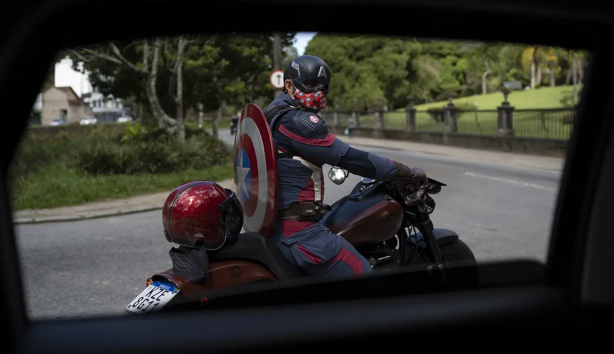 Petugas polisi militer Everaldo Pinto, berkostum superhero Captain America, mengendarai sepeda motornya di tengah pandemi COVID-19 di Petropolis, Rio de Janeiro, Brasil, Kamis (15/4/2021). Pinto memberitahu anak-anak tentang perlunya melindungi diri dari virus corona. (AP Photo/Silvia Izquierdo)
