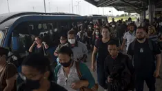 Para komuter berjalan di stasiun BRT Recreio pada hari pertama pencabutan aturan wajib masker di luar ruangan, di Rio de Janeiro, Brasil, Kamis (28/12/2021). Pencabutan aturan wajib masker ini efektif berlaku pada Kamis (28/10) waktu setempat. (MAURO PIMENTEL / AFP)