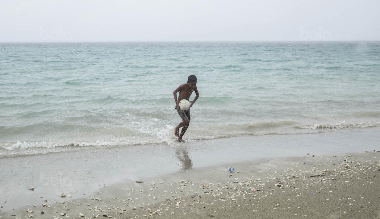 Pesepak bola SSB Tulehu Putra, Alghy Nahumarury, mengambil bola saat latihan di tepi Pantai Tial, Maluku, Rabu (16/11/2017). Bagi Alghy sepak bola adalah semangatnya untuk bisa bermimpi meski hidup dalam keterbatasan. (Bola.com/Vitalis Yogi Trisna)