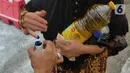 Warga mencelupkan jari ke dalam tinta usai membeli minyak goreng di Polsek Tebet, Jakarta Selatan, Jumat (4/3/2022). Polres Metro Jakarta Selatan akan menggelar operasi pasar minyak goreng selama enam hari, terhitung mulai hari in, 4 hingga 9 Februari mendatang. (Liputan6.com/Herman Zakharia)