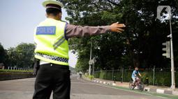 Petugas gabungan mengarahkan pengguna sepeda saat pengalihan jalur pesepeda di kawasan Sudirman-Thamrin, Jakarta, Minggu (5/9/2021). Pemberlakuan jalur ganjil genap pada masa PPKM membuat pengguna sepeda dilarang melintasi kawasan ganjil-genap pagi ini. (Liputan6.com/Angga Yuniar)