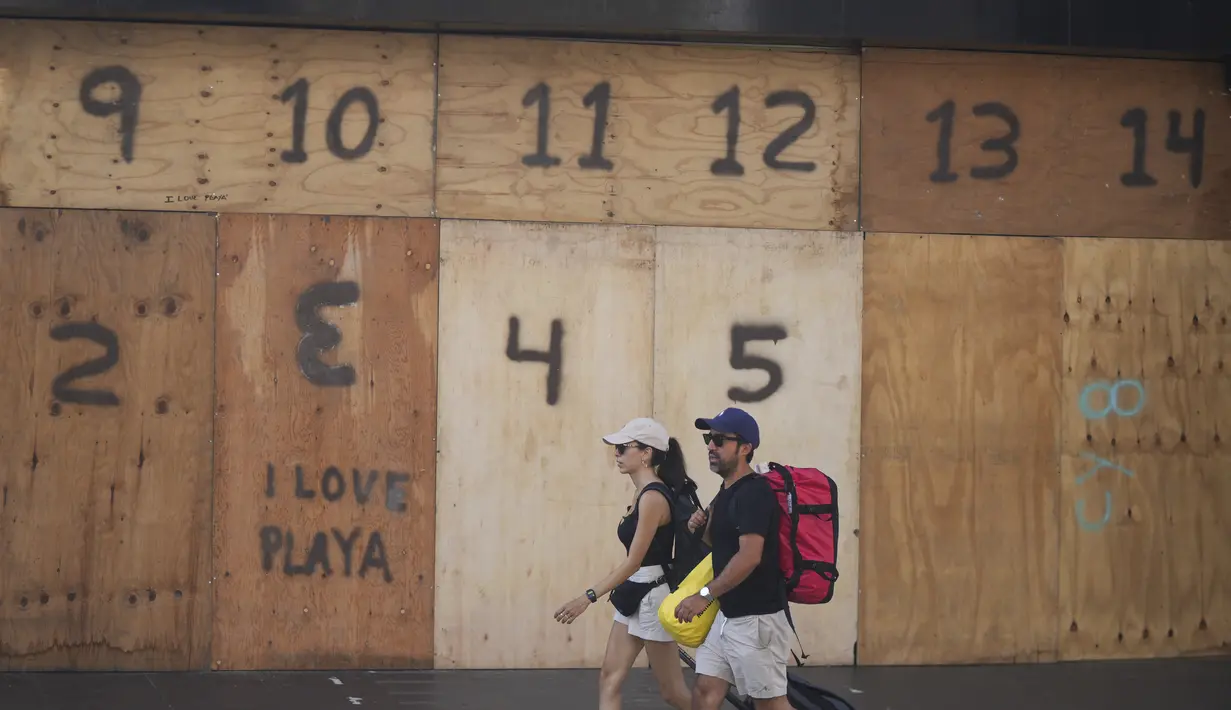Orang-orang berjalan melewati etalase toko suvenir yang dipasangi papan persiapan kedatangan Badai Beryl, di Playa del Carmen, Meksiko, Kamis (4/7/2024). (AP Photo/Fernando Llano)