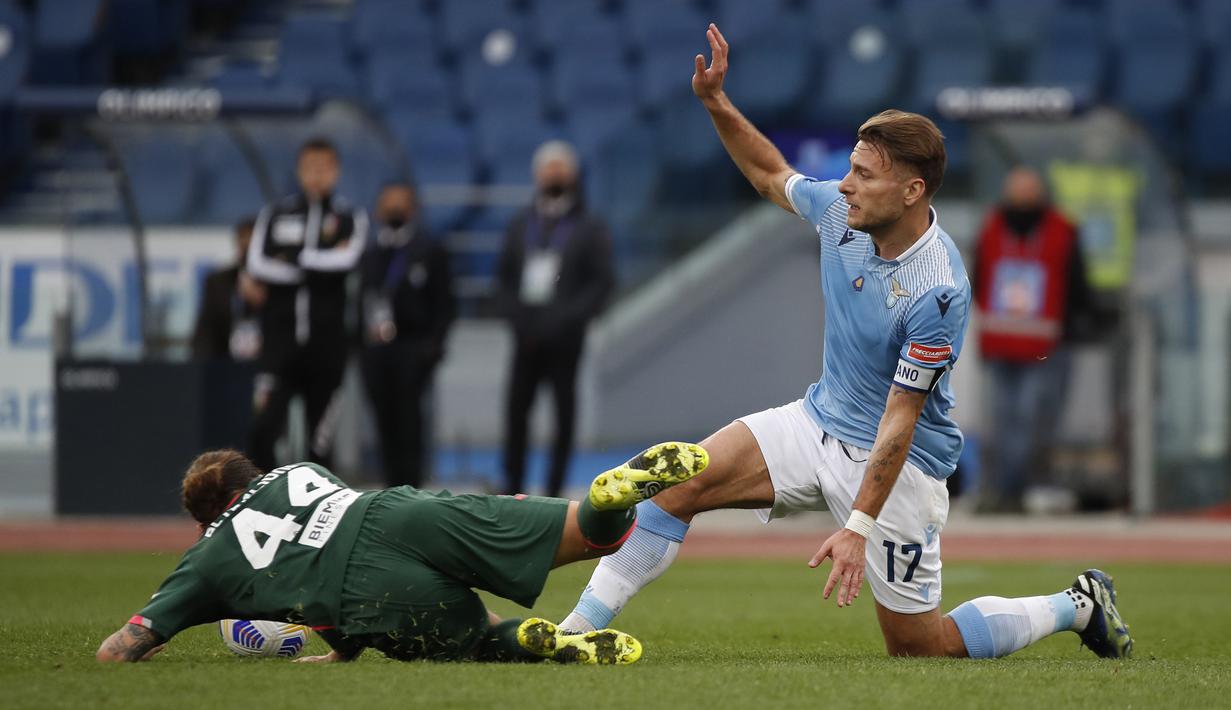 Striker Lazio, Ciro Immobile (kanan) berebut bola dengan gelandang Crotone, Jacopo Petriccione dalam laga lanjutan Liga Italia 2020/2021 pekan ke-27 di Olimpico Stadium, Roma, Jumat (12/3/2021). Lazio menang 3-2 atas Crotone. (AP/Alessandra Tarantino)