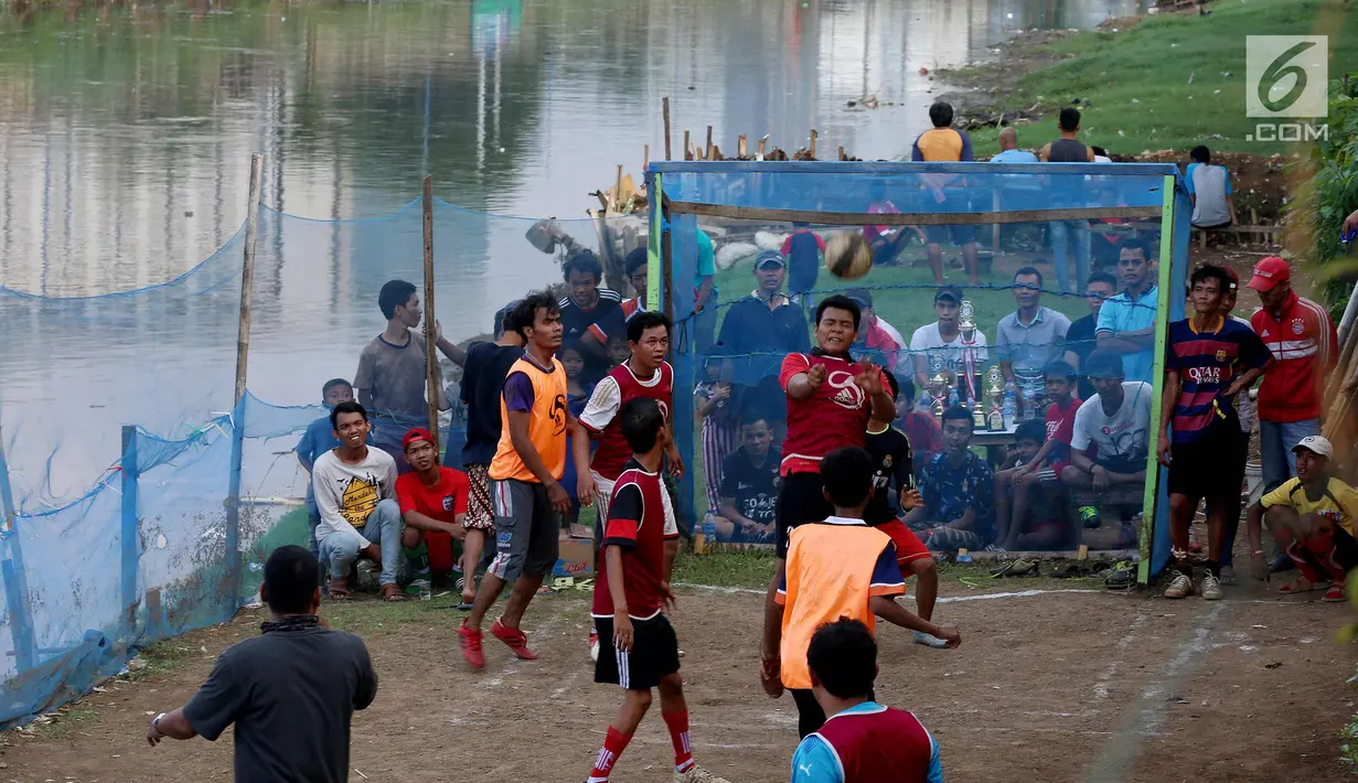 Warga bermain dalam kompetisi sepak bola di pinggir Kali Banjir Kanal Barat, Jakarta, Sabtu (5/11). Minimnya sarana bermain sepak bola mengakibatkan warga terpaksa memanfaatkan lahan di pinggir kali tersebut untuk bermain. (Liputan6.com/Johan Tallo)