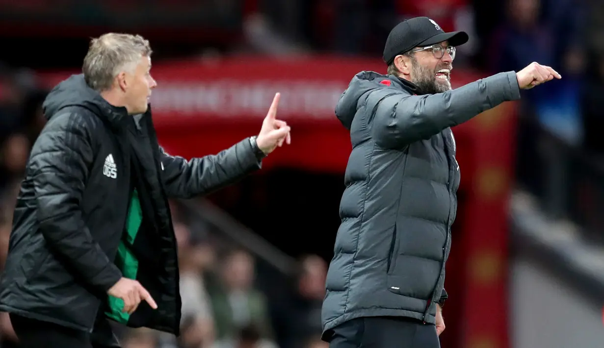 Pelatih Liverpool Jurgen Klopp (kanan) dan pelatih Manchester United Ole Gunnar Solskjaer (kiri) memberi isyarat kepada anak asuh mereka selama pertandingan Liga Inggris di Stadion Old Trafford, Manchester, Inggris, Minggu (20/10/2019). Pertandingan berakhir dengan skor 1-1. (AP Photo/Jon Super)