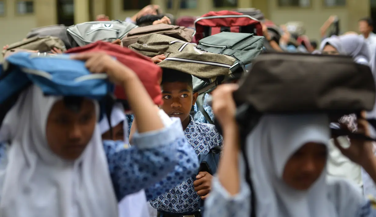 Sejumlah siswa berlarian menyelamatkan diri saat simulasi bencana gempa dan tsunami di sebuah sekolah di Banda Aceh, Aceh, Rabu (9/10/2019). Para siswa dibekali wawasan tanggap darurat bencana dan pemberian pertolongan pertama pada korban gempa. (Photo by CHAIDEER MAHYUDDIN / AFP)