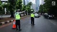 Petugas kepolisian mengarahkan kendaraan saat pengalihan arus di Jalan Jenderal Sudirman, Jakarta, Minggu (31/12). Pengalihan terkait malam puncak perayaan pergantian tahun di kawasan Bundaran HI hingga Jalan MH Thamrin. (Liputan6.com/Helmi Fithriansyah)