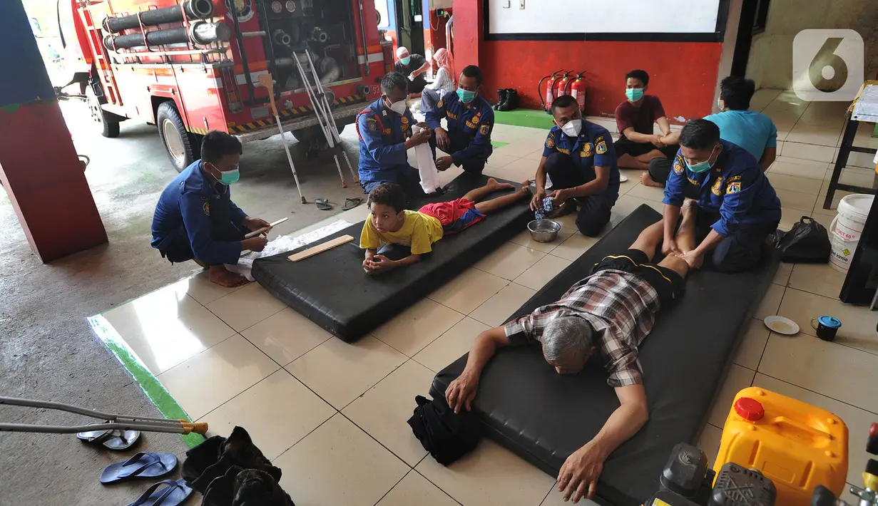 Para petugas Damkar mengobati warga yang mengalami patah tulang di Pos Damkar Ciganjur, Jagakarsa, Jakarta Selatan, Rabu (2/12/2020). Petugas Damkar memijat khas Cimande dengan bayaran seikhlasnya, pengobatan dilakukan di sela waktu senggang petugas Damkar. (merdeka.com/Arie Basuki)