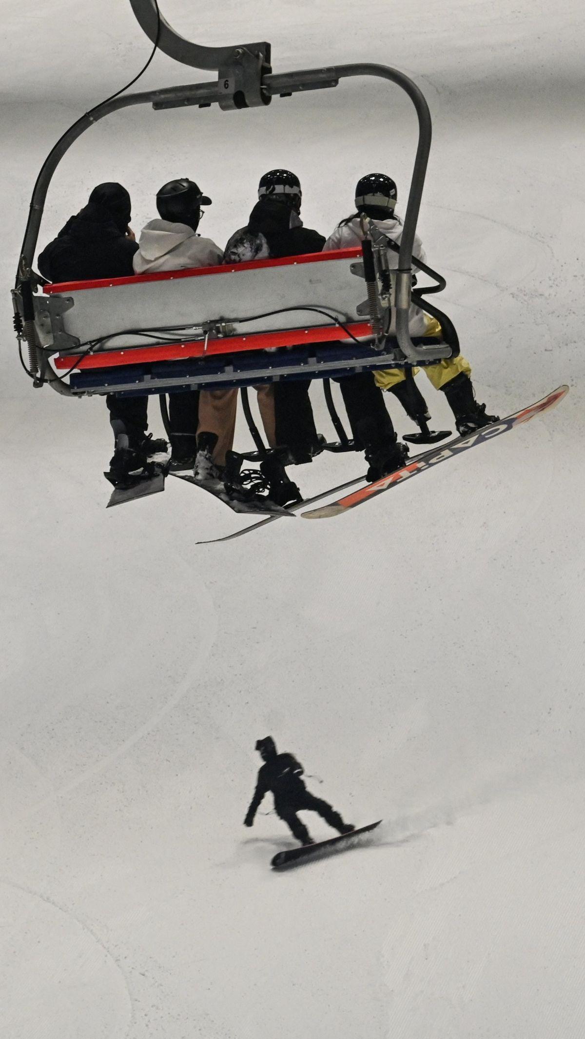 Sejumlah pengunjung menggunakan kereta gantung menuju puncak seluncur es pada&nbsp;Shanghai L+SNOW Indoor Skiing Theme Resort.&nbsp;Foto: Hector Retamal/AFP